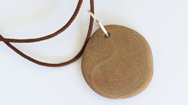 Round stone pendant on a brown cord. Summer wibes