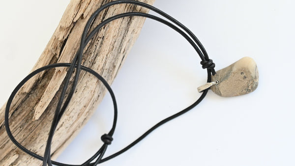 Beige seashore pebble with patterns on black leather cord