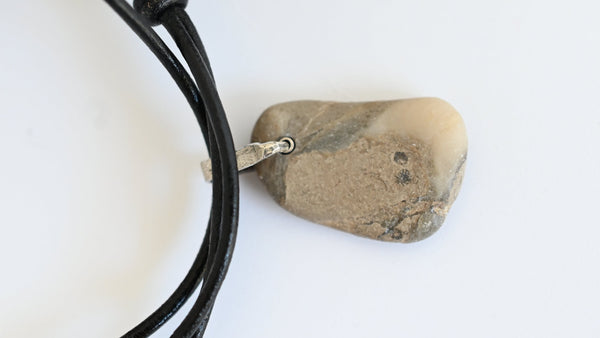 Beige seashore pebble with patterns on black leather cord