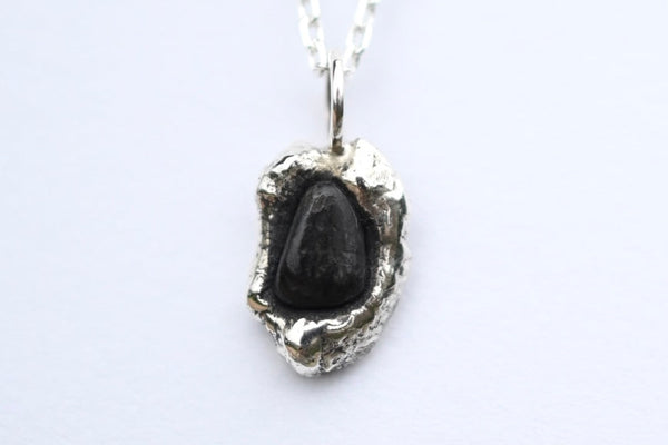 Sterling silver cylindrical pendant with triangle form black beach pebble on a silver chain