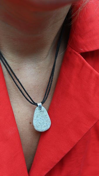 Silver pendant on a black cotton cord against a red fabric. Summer vibes. Handmade jewellery 