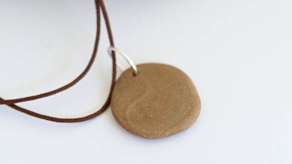 Round brown pendant on a synthetic brown cord. Summer vibes