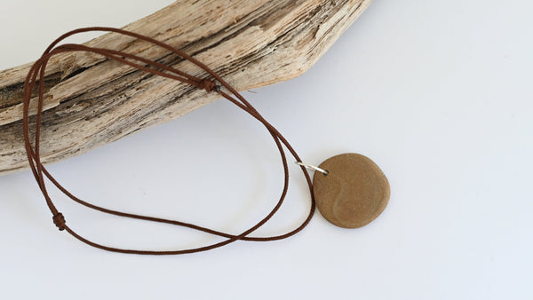Necklace with a round brown seashore pebble pendant on a brown cord