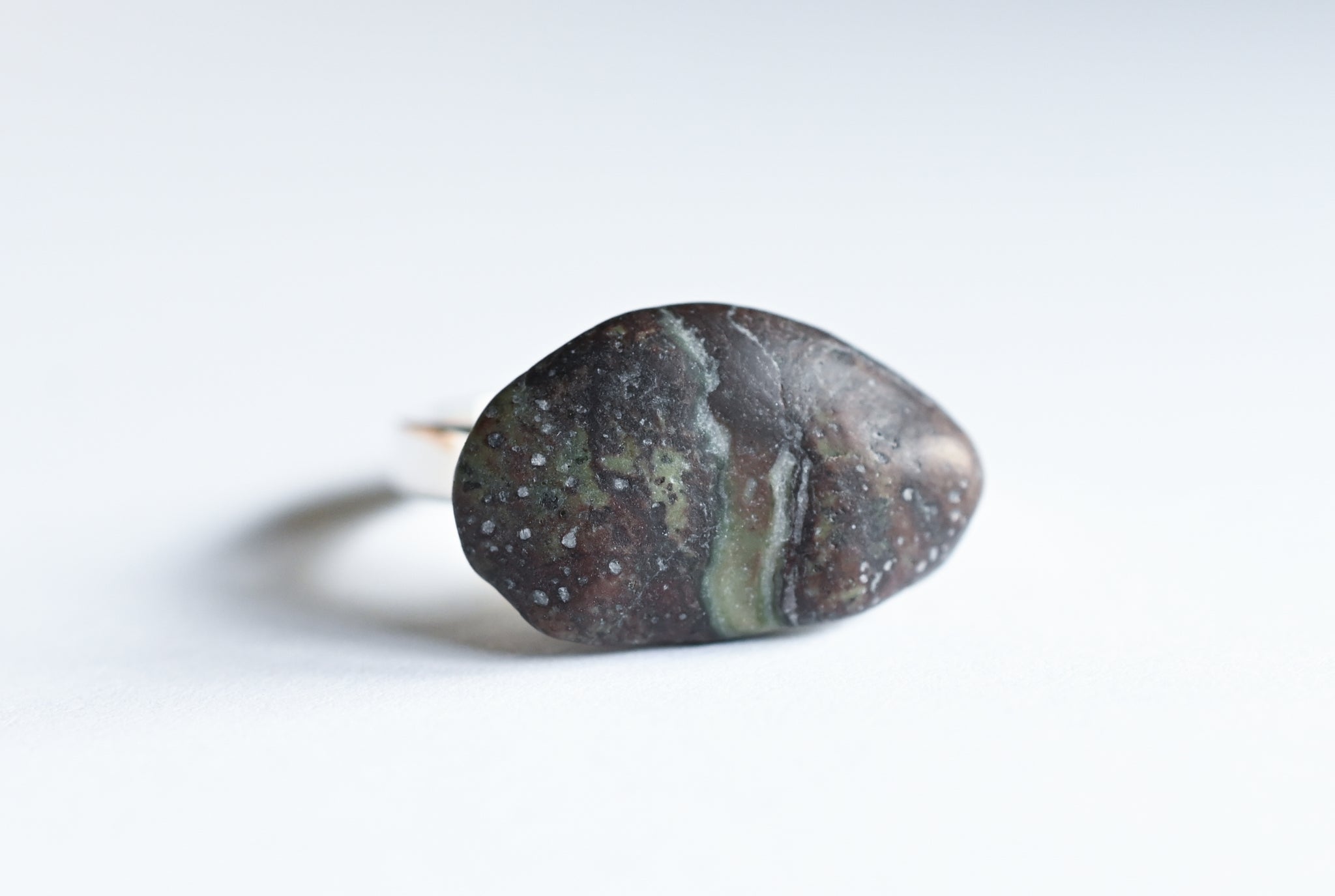 Handmade silver ring with a beach oval-shaped pebble in purple and green colours