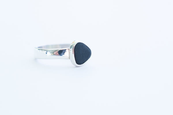 Silver ring with a black triangle seashore stone. Pebbles.
