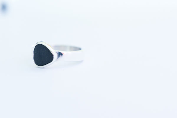 Silver ring with a black triangle seashore stone. Pebbles.