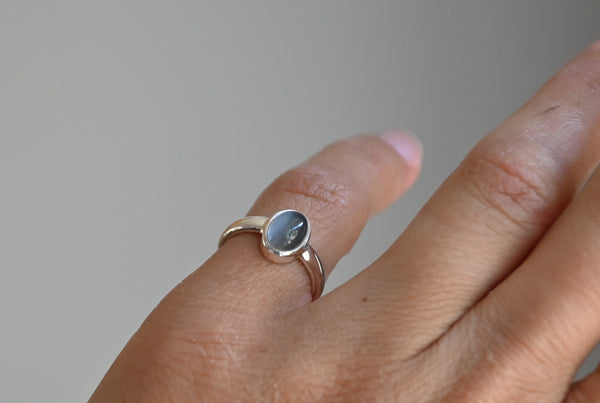 Silver ring with a grey moonstone on a finger 