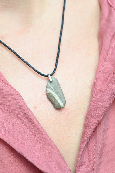 Necklace with a seashore pebb;e pendant on a person wearing a pink garment