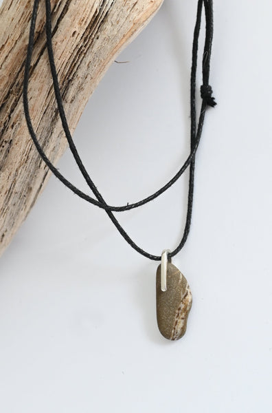 Black cord silver necklace with seashore pebble on a piece of driftwood 